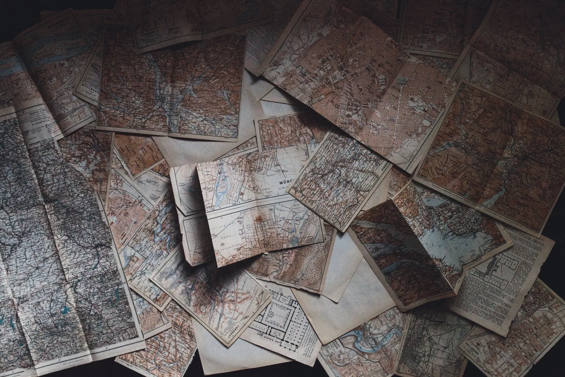 De vieilles cartes routières étalées sur une table sombre.